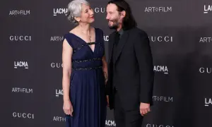 Keanu Reeves i jego żona Alexandra Grant patrzą na siebie z uśmiechem na tle logo Gucci i Art+Film.