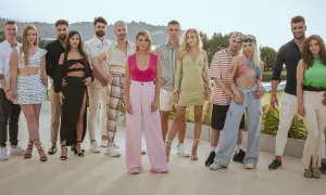 Grupa młodych ludzi pozuje do zdjęcia. Widać ich stroje, uśmiechy, ale czego nie widać w kamerach podczas nagrań reality show?