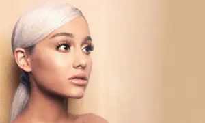 Portret Ariany Grande z blond włosami spiętymi w kucyk, patrzącej w bok.