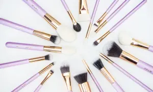 Recenzja pędzli do makijażu które poleca każda polska beauty-influencerka. Fioletowe pędzle z złotymi okuciami ułożone na białym tle.