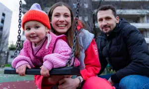 Rodzina na placu zabaw. Dziecko w różowym sweterku i czapce, obok uśmiechnięta mama i tata. To przykład listy dzieci gwiazd, które pracują w zwykłych zawodach poza branżą.