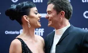Katy Perry i Orlando Bloom patrzą na siebie z uśmiechem na czerwonym dywanie.