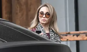 Cleo bez makijażu, w okularach i panterkowej chuście, trzyma telefon.