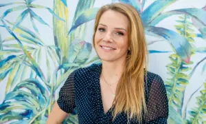 Uśmiechnięta Hanna Zborowska Neves na tle tropikalnej tapety.
