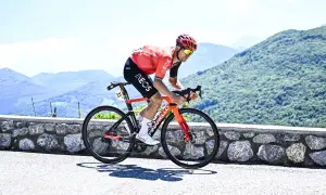Michał Kwiatkowski, piosenkarz, ściga się rowerem po górskiej drodze.