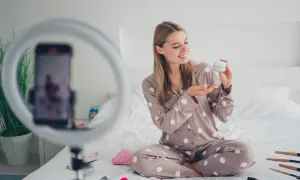 Uśmiechnięta influencerka z Polski zdradza tajemnicę egzotycznej urody, prezentując krem. Wokół kosmetyki i ring light.