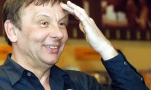 Uśmiechnięty mężczyzna w czarnej koszuli, która gwiazda estrady ogłosiła zakończenie kariery podczas ostatniego występu.