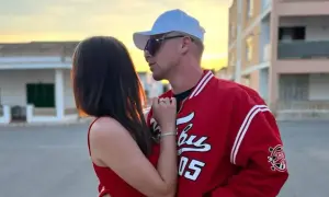 Para zapatulona na tle budynków i zachodzącego słońca. Mężczyzna w czapce i kurtce baseballowej.