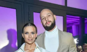 Para na tle fioletowych świateł. On, z zarostem i łysą głową, w beżowej marynarce. Ona, z blond włosami, w białej koszuli. Maciej Pela wiek nieznany.