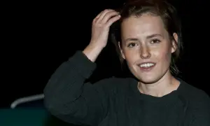 Olga Frycz, młoda kobieta z piegami, uśmiecha się, poprawiając włosy. Na jej dłoni plaster.