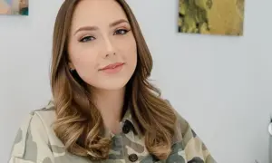 Uśmiechnięta Hailie Jade Scott Mathers w kurtce moro, z lekko pofalowanymi brązowymi włosami.