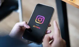 Dłoń trzyma smartfon z logo Instagrama i Meta. Zastanawiasz się, ile zarabiają polscy influencerzy za jeden post sponsorowany?