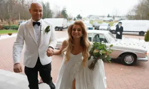 Szczęśliwi Adrian i jego wybranka, świeżo po ślubie od pierwszego wejrzenia, wychodzą na zewnątrz. Ona trzyma bukiet, on ją prowadzi.