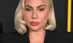 Lady Gaga, z blond włosami i makijażem, w czarnej marynarce. Czy Lady Gaga ma dziecko? To pytanie nurtuje fanów.