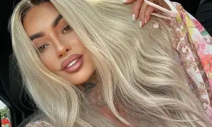Ania Królowe Życia z blond włosami i tatuażem na szyi, w kwiecistej bluzce.