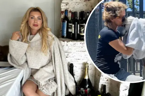Eva Halina Rich w swetrze siedzi przy stole, a obok niej wesoło przytula białego zwierzaka.
