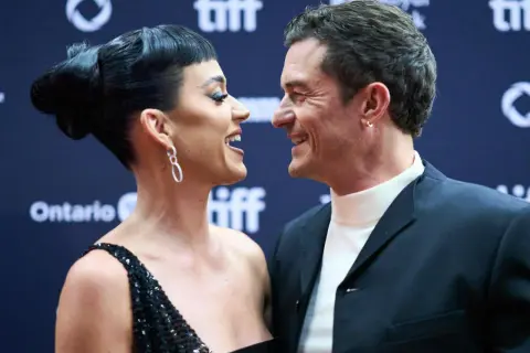 Katy Perry i Orlando Bloom patrzą na siebie z uśmiechem na czerwonym dywanie.