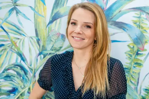 Uśmiechnięta Hanna Zborowska Neves na tle tropikalnej tapety.