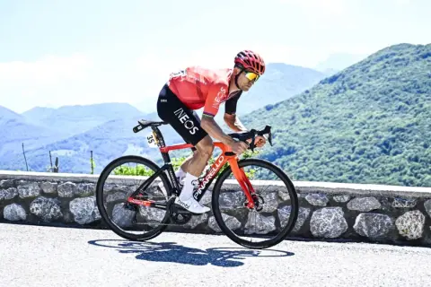 Michał Kwiatkowski, piosenkarz, ściga się rowerem po górskiej drodze.