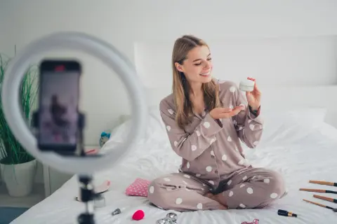 Uśmiechnięta influencerka z Polski zdradza tajemnicę egzotycznej urody, prezentując krem. Wokół kosmetyki i ring light.