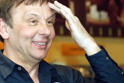 Uśmiechnięty mężczyzna w czarnej koszuli, która gwiazda estrady ogłosiła zakończenie kariery podczas ostatniego występu.