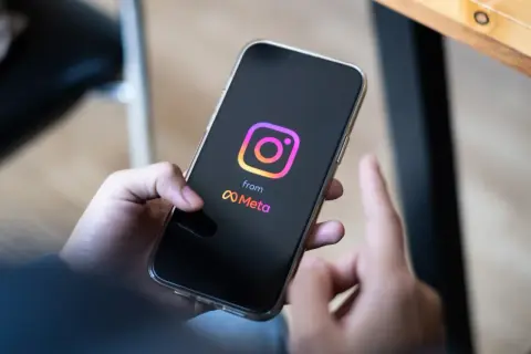 Dłoń trzyma smartfon z logo Instagrama i Meta. Zastanawiasz się, ile zarabiają polscy influencerzy za jeden post sponsorowany?
