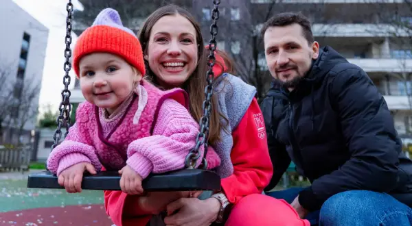 Rodzina na placu zabaw. Dziecko w różowym sweterku i czapce, obok uśmiechnięta mama i tata. To przykład listy dzieci gwiazd, które pracują w zwykłych zawodach poza branżą.