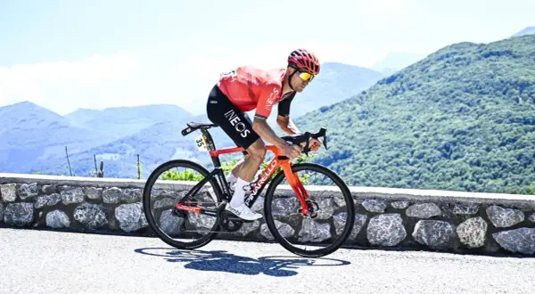 Michał Kwiatkowski, piosenkarz, ściga się rowerem po górskiej drodze.