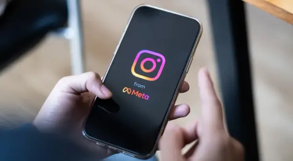Dłoń trzyma smartfon z logo Instagrama i Meta. Zastanawiasz się, ile zarabiają polscy influencerzy za jeden post sponsorowany?