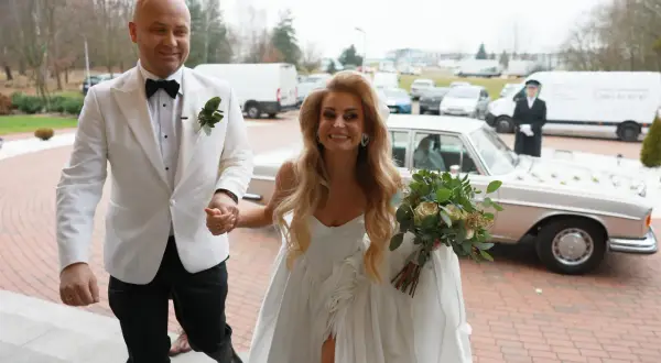 Szczęśliwi Adrian i jego wybranka, świeżo po ślubie od pierwszego wejrzenia, wychodzą na zewnątrz. Ona trzyma bukiet, on ją prowadzi.