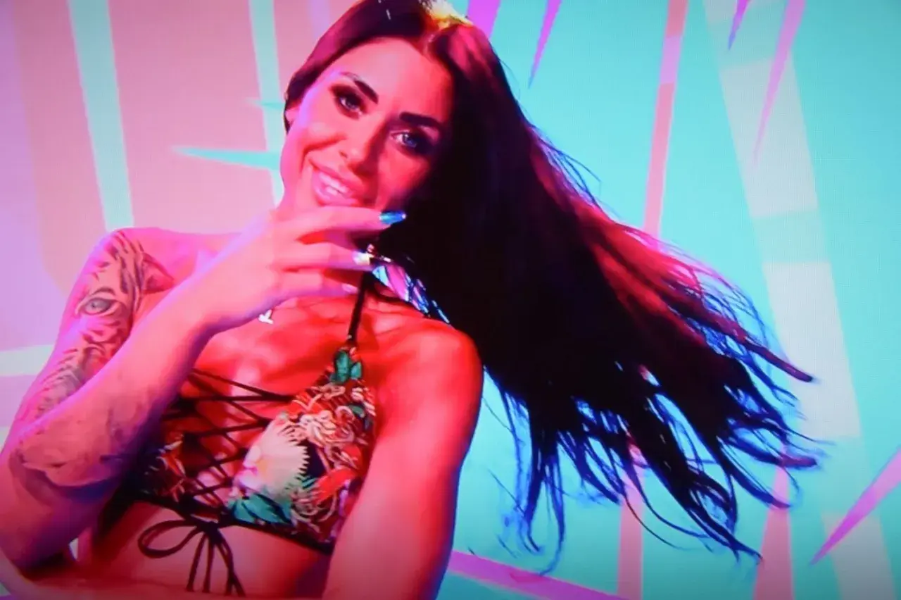 Stella z Love Island w kolorowym bikini, z tatuażem tygrysa na ramieniu, uśmiecha się do kamery.