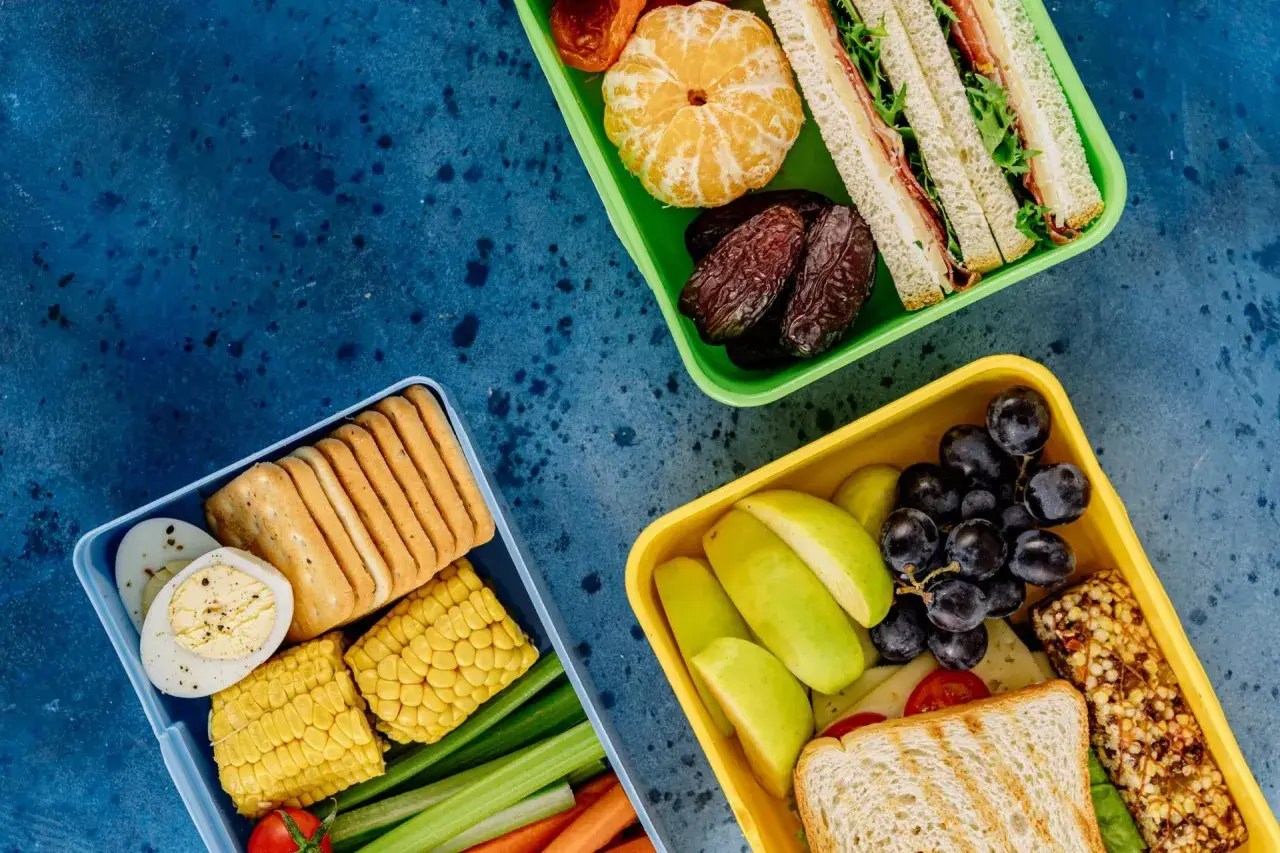 Czy warto kupić catering dietetyczny od najpopularniejszej trenerki fitness? Trzy pudełka pełne zdrowych przekąsek: kanapki, owoce, warzywa, jajka, krakersy.