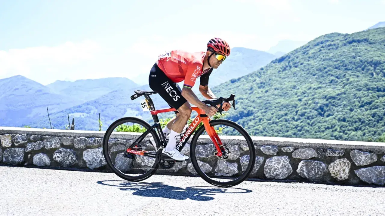 Michał Kwiatkowski, piosenkarz, ściga się rowerem po górskiej drodze.