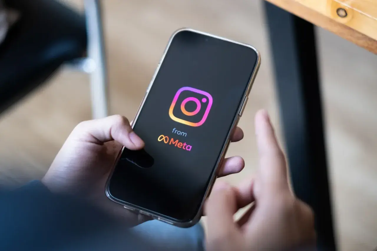 Dłoń trzyma smartfon z logo Instagrama i Meta. Zastanawiasz się, ile zarabiają polscy influencerzy za jeden post sponsorowany?