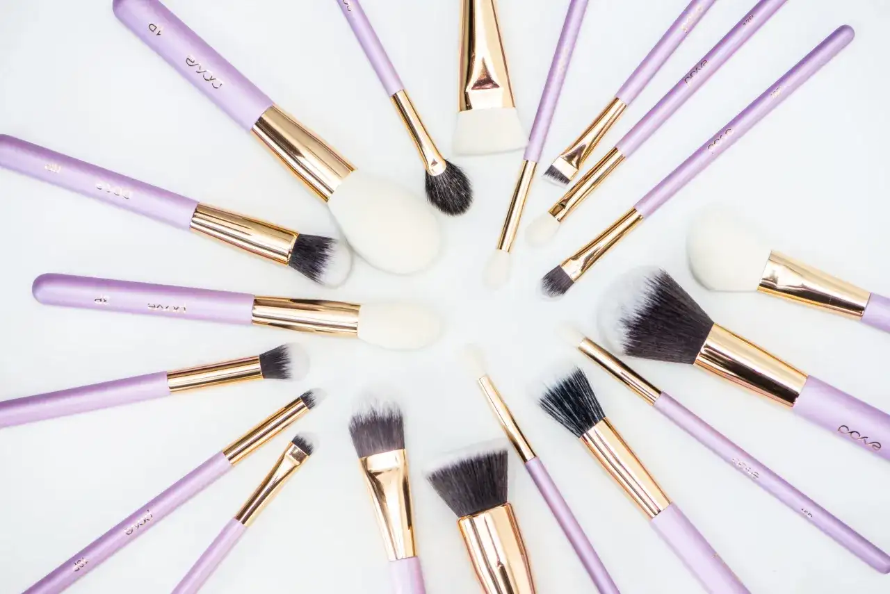 Recenzja pędzli do makijażu które poleca każda polska beauty-influencerka. Fioletowe pędzle z złotymi okuciami ułożone na białym tle.