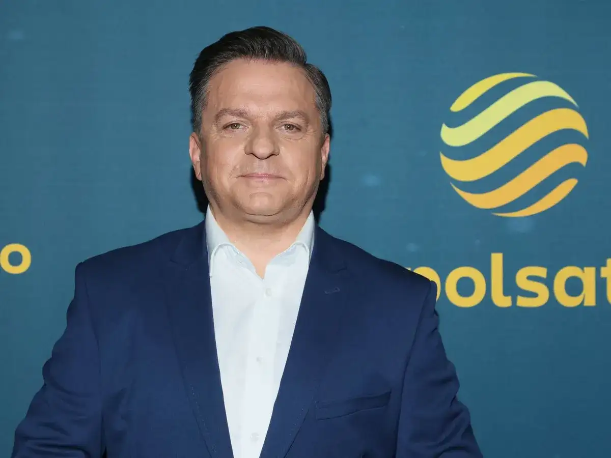 Mężczyzna w garniturze przed logo Polsatu. Czy to wyjaśnia, dlaczego znany prezenter został zawieszony w obowiązkach służbowych?