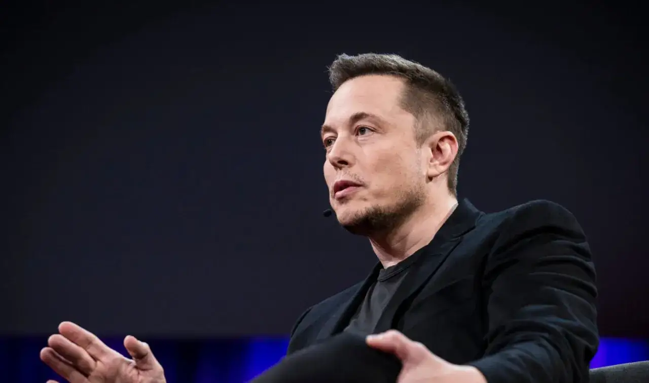 Elon Musk, wizjoner techno mechanicus, przemawia z pasją, gestykulując rękami.