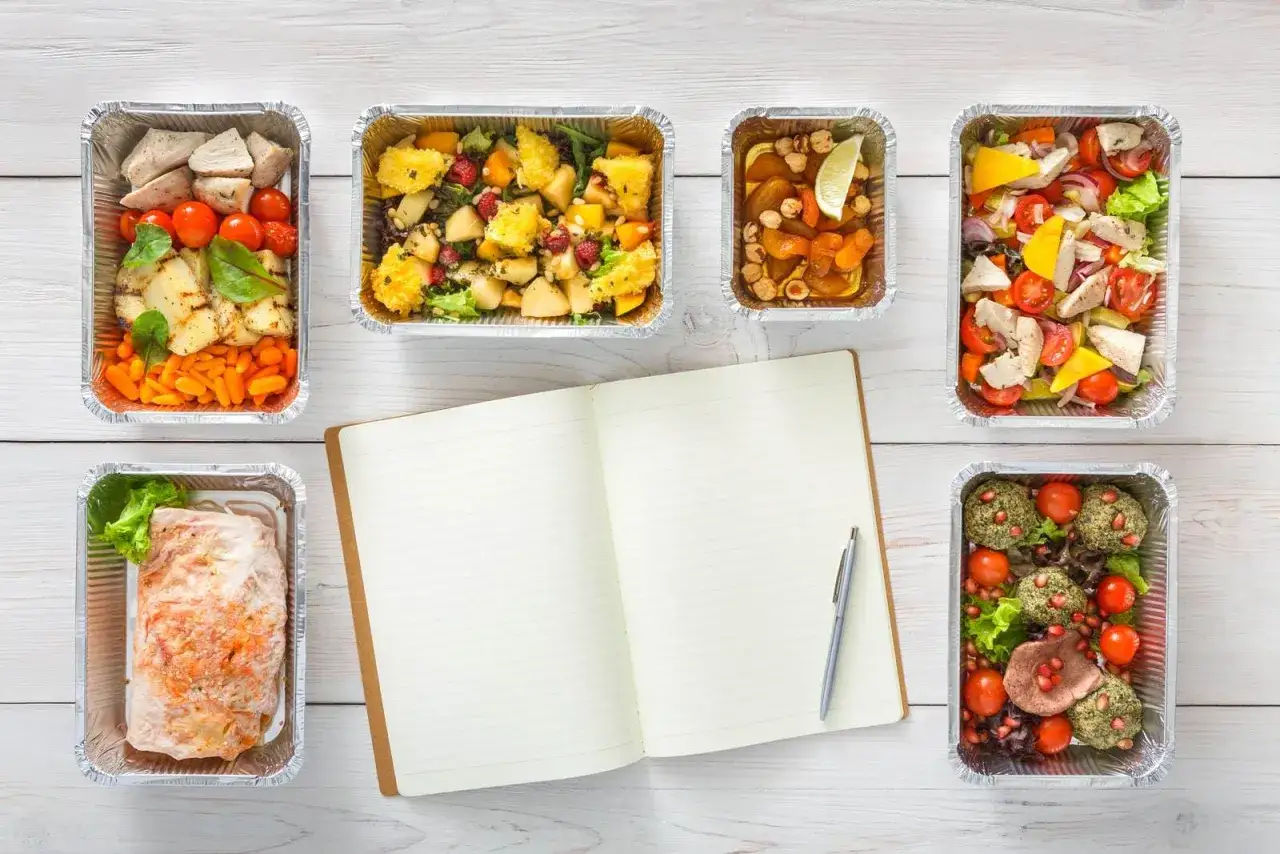 Sześć pojemników z jedzeniem i notatnik. Czy warto kupić catering dietetyczny od najpopularniejszej trenerki fitness?
