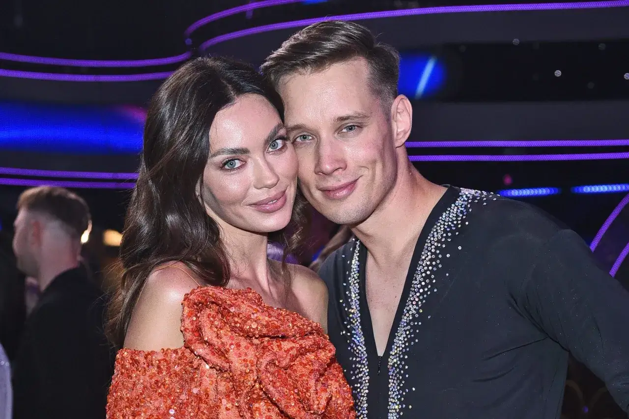 Edyta Zając i jej partner, uśmiechnięci, pozują do zdjęcia na tle sceny.