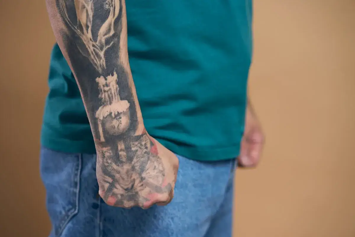 Tatuaże na ramieniu mężczyzny, ukazujące świecę i symbolikę, mogą skrywać ukryte znaczenie tatuaży popularnych raperów z polski.
