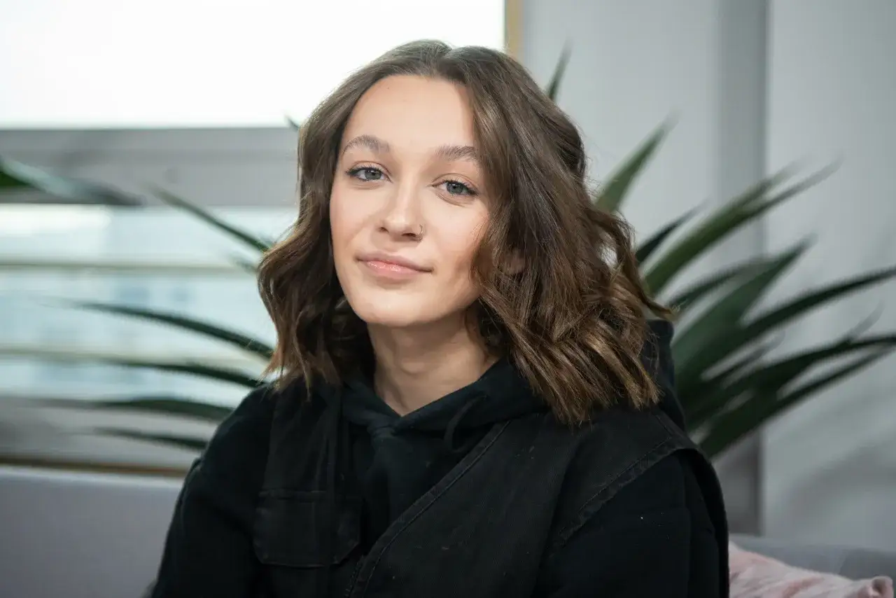 Uśmiechnięta Fabienne Marta Wiśniewska w czarnej bluzie z kapturem, z delikatnym piercingiem w nosie.