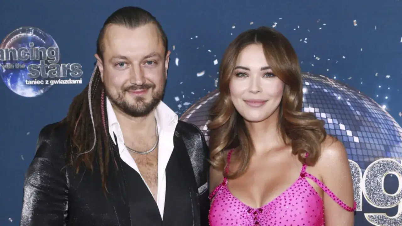 Sandra Kubicka i Baron uśmiechają się do zdjęcia na tle błyszczącej kuli dyskotekowej i napisu