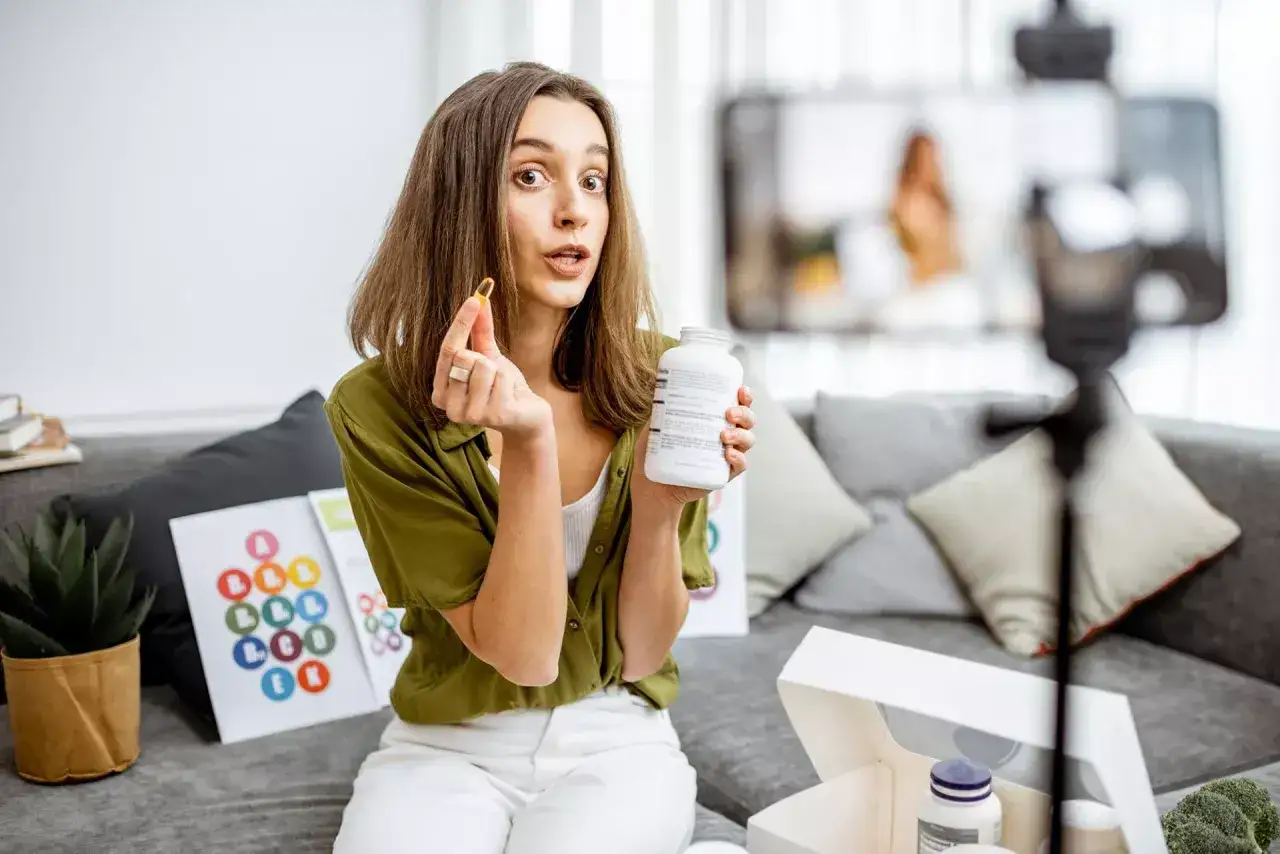 Influencerka pokazuje suplementy, zastanawiając się, czy suplementy diety od gwiazd instagrama są bezpieczne dla zdrowia.