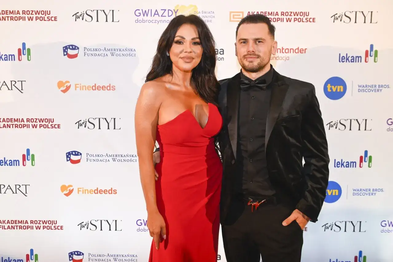Sylwia Bomba w czerwonej sukni i jej partner na ściance.