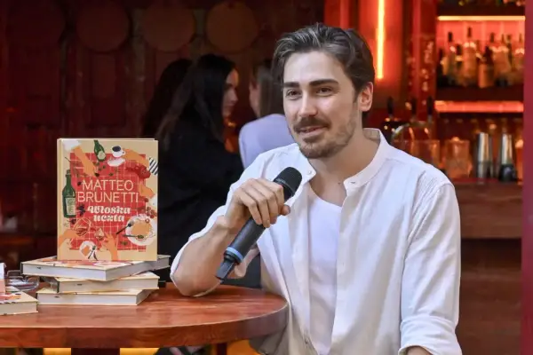 Matteo Brunetti z mikrofonem obok swojej książki "Włoska uczta". Czy popularny kucharz naprawdę uczył się gotować w zagranicznej rodzinie?
