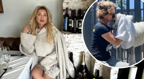 Eva Halina Rich w swetrze siedzi przy stole, a obok niej wesoło przytula białego zwierzaka.