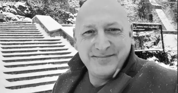 Jacek Wójcik, w zimowej scenerii, na tle zaśnieżonych schodów. Wiek nie jest widoczny, ale uśmiech sugeruje radość.