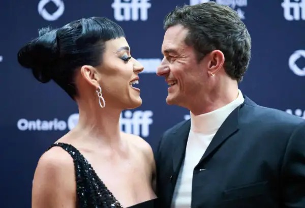 Katy Perry i Orlando Bloom patrzą na siebie z uśmiechem na czerwonym dywanie.