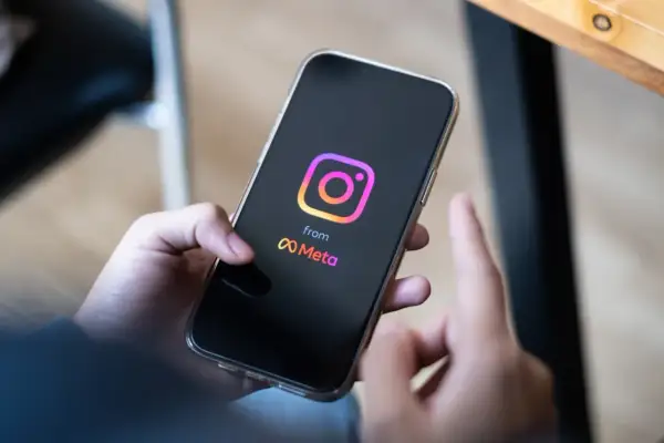 Dłoń trzyma smartfon z logo Instagrama i Meta. Zastanawiasz się, ile zarabiają polscy influencerzy za jeden post sponsorowany?